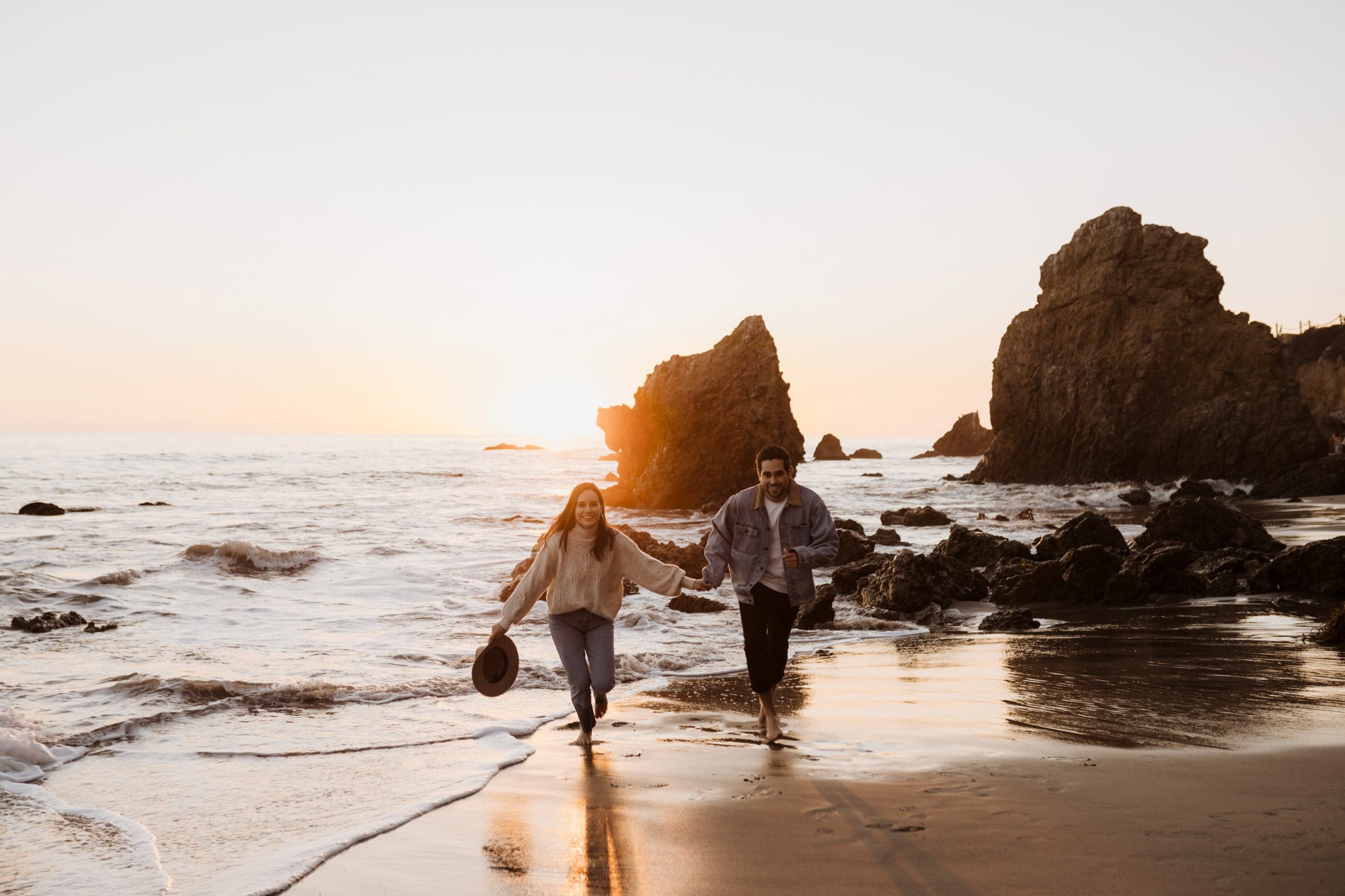 Couple Running on El Matador Beach | Kelly O'Connor Photography | Austin Based Wedding Photographer | Malibu, California Engagement Session | couples photos, bride to be, engagement photos, outfit ideas for engagement photos, destination photo session, beach photos, grainy photos, photos of couple on beach | via kellyoconnorphotography.com