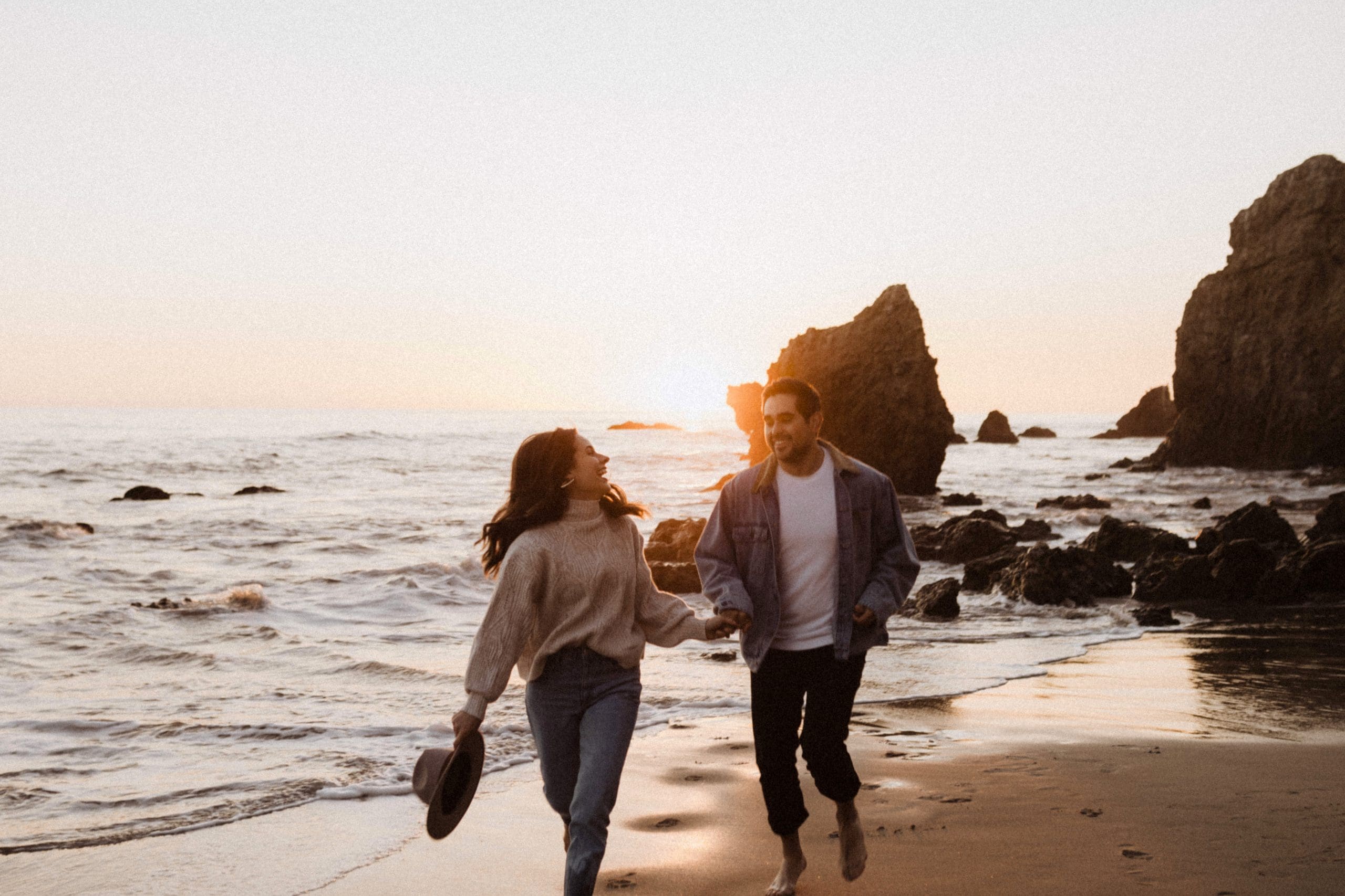 Couple Running on El Matador Beach | Kelly O'Connor Photography | Austin Based Wedding Photographer | Malibu, California Engagement Session | couples photos, bride to be, engagement photos, outfit ideas for engagement photos, destination photo session, beach photos, grainy photos, photos of couple on beach | via kellyoconnorphotography.com