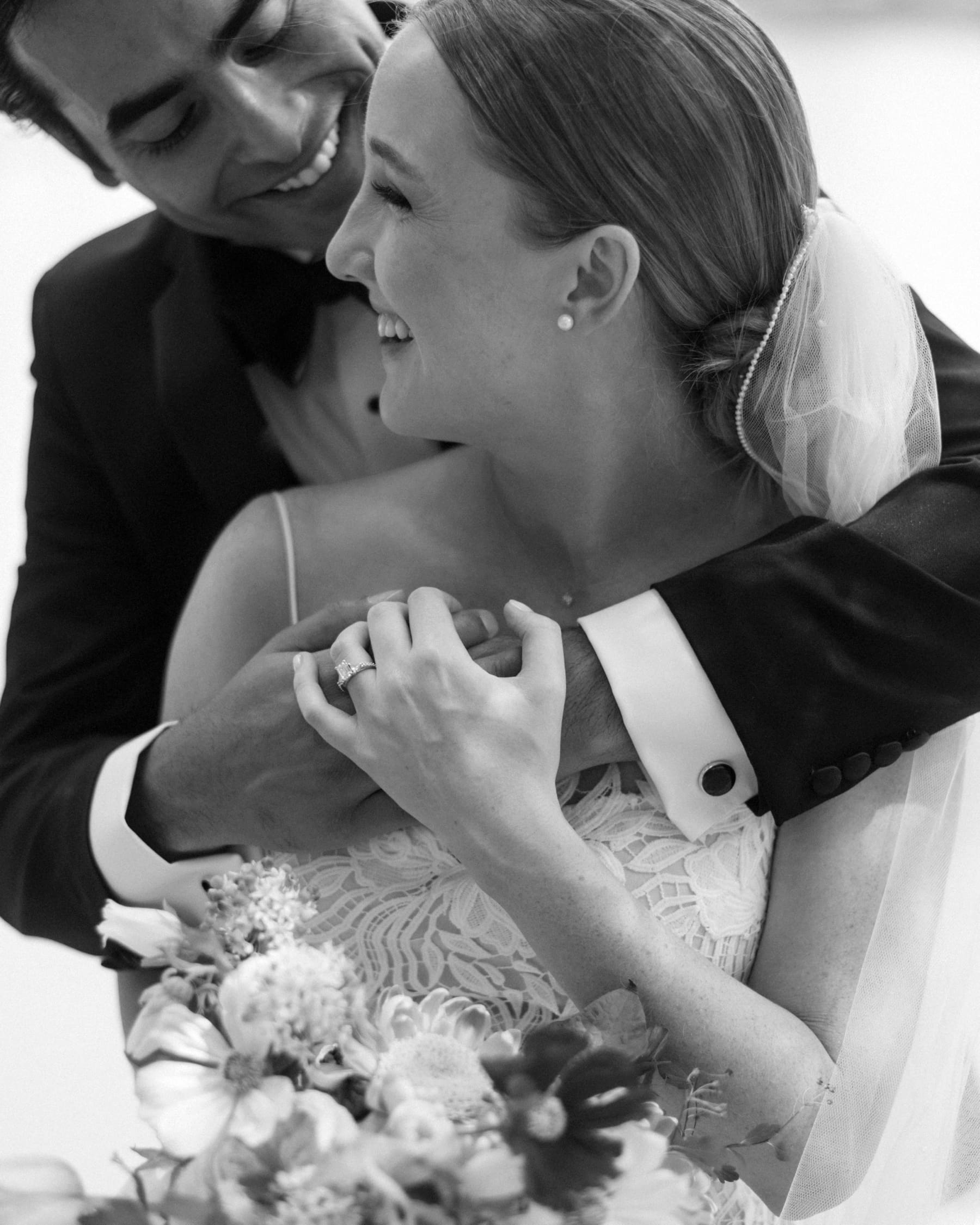 Bride looking over shoulder at groom while he has his arms around her