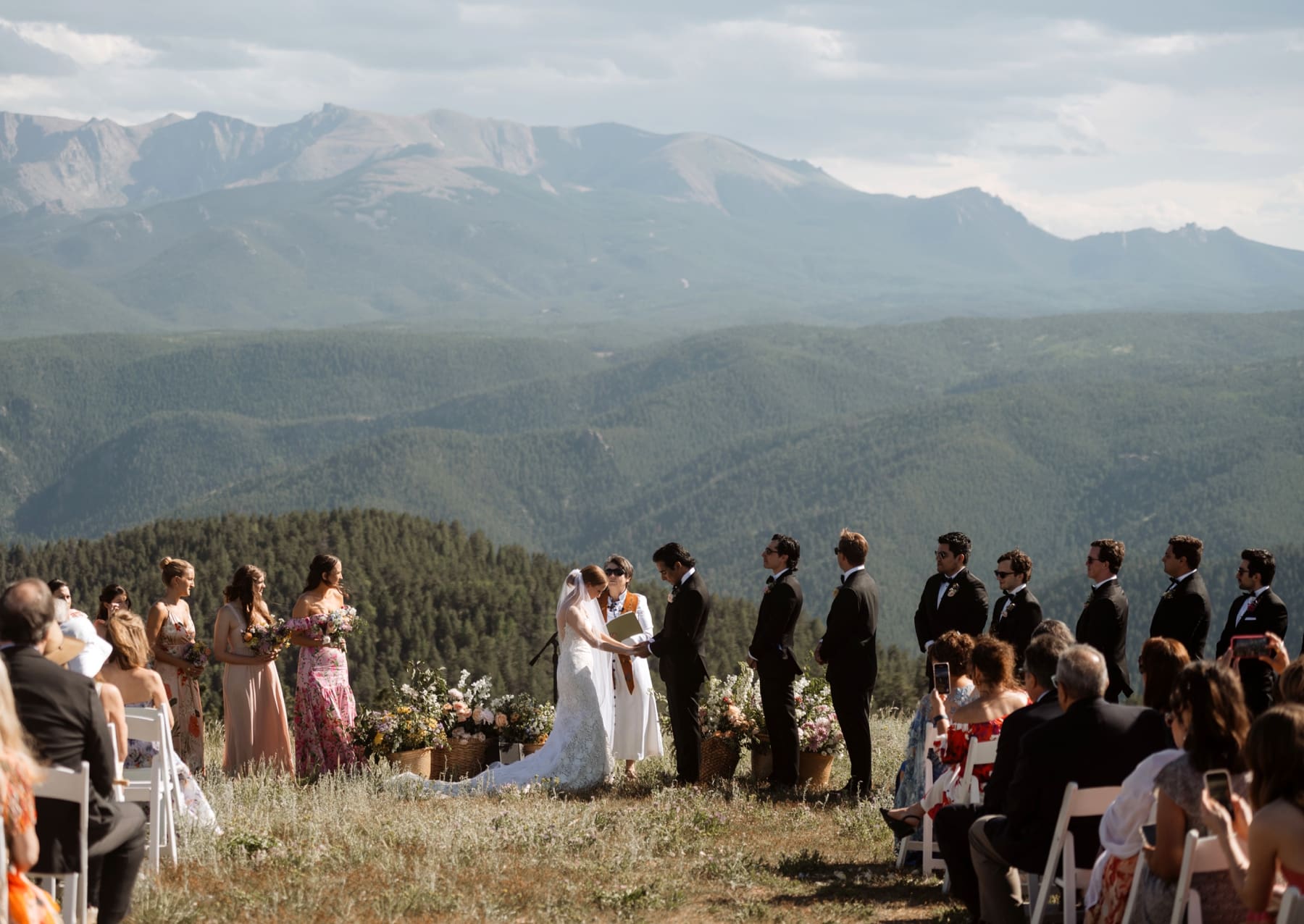 Bride and groom holding hands during ceremony in front of Colorado mountains