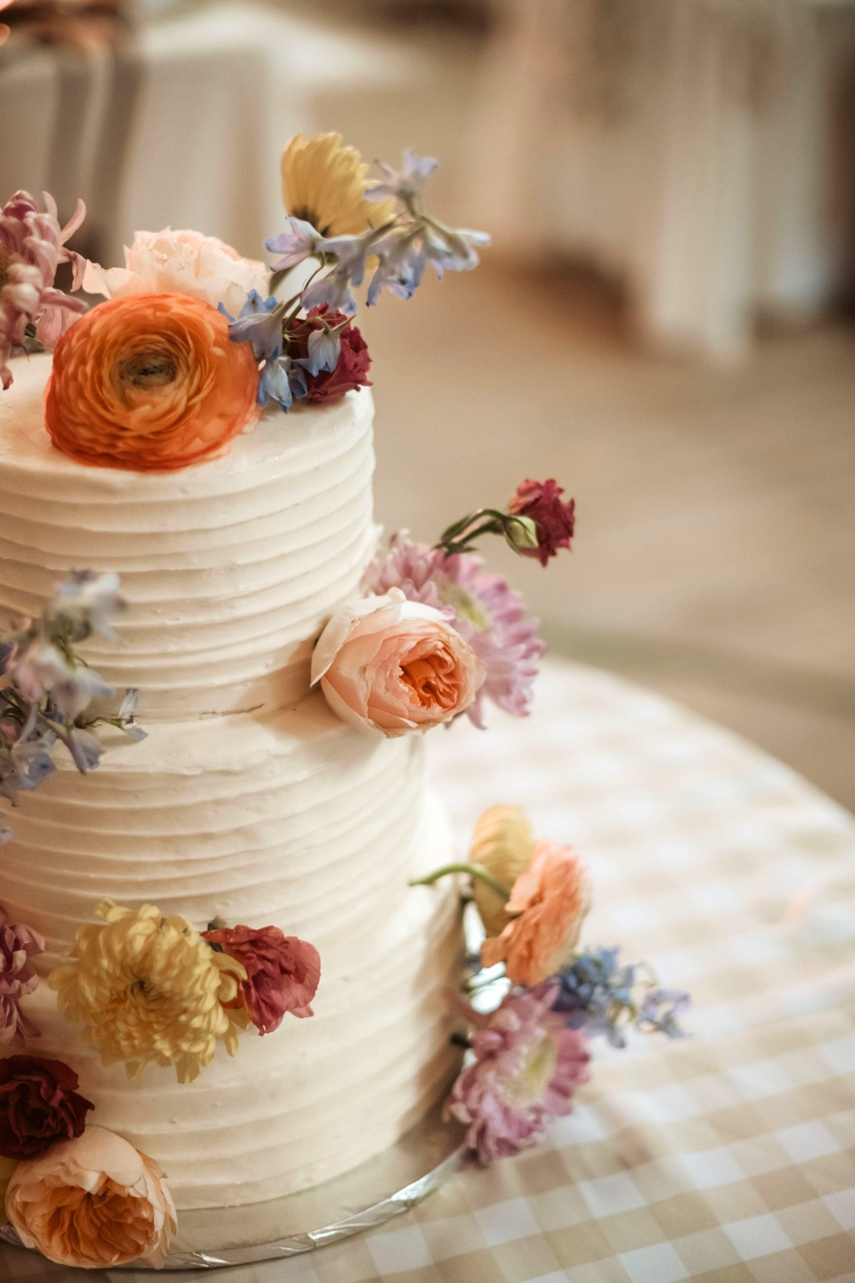 Three tier wedding cake with ribbon frosting and whimsical fresh flowers