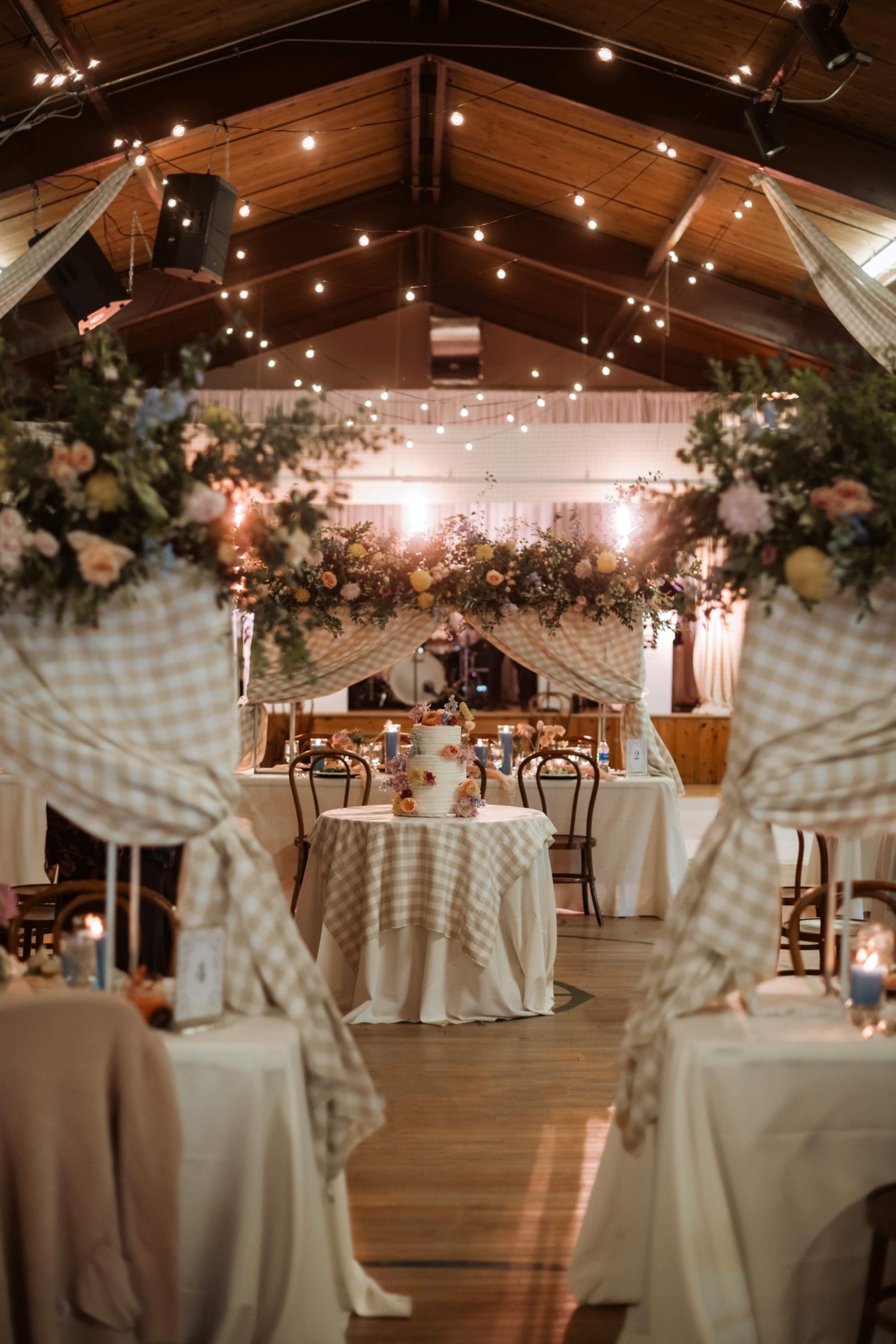 Wedding reception with whimsical flowers, twinkle lights, and gingham draping and linens