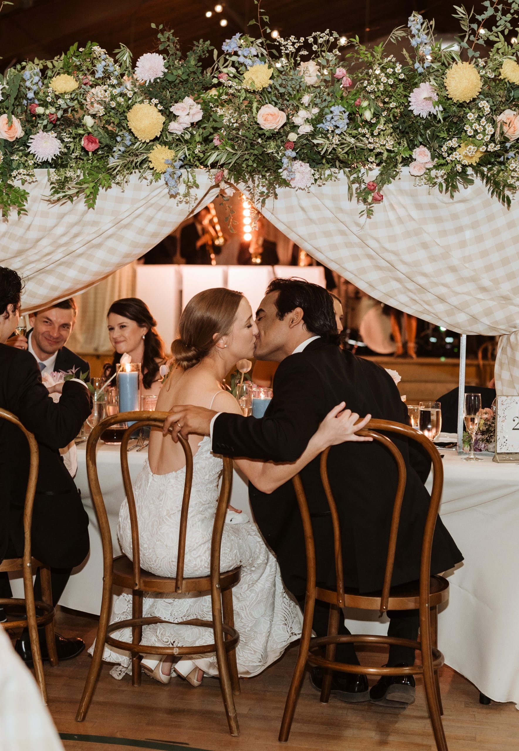 Bride and groom kissing while sitting at table during reception