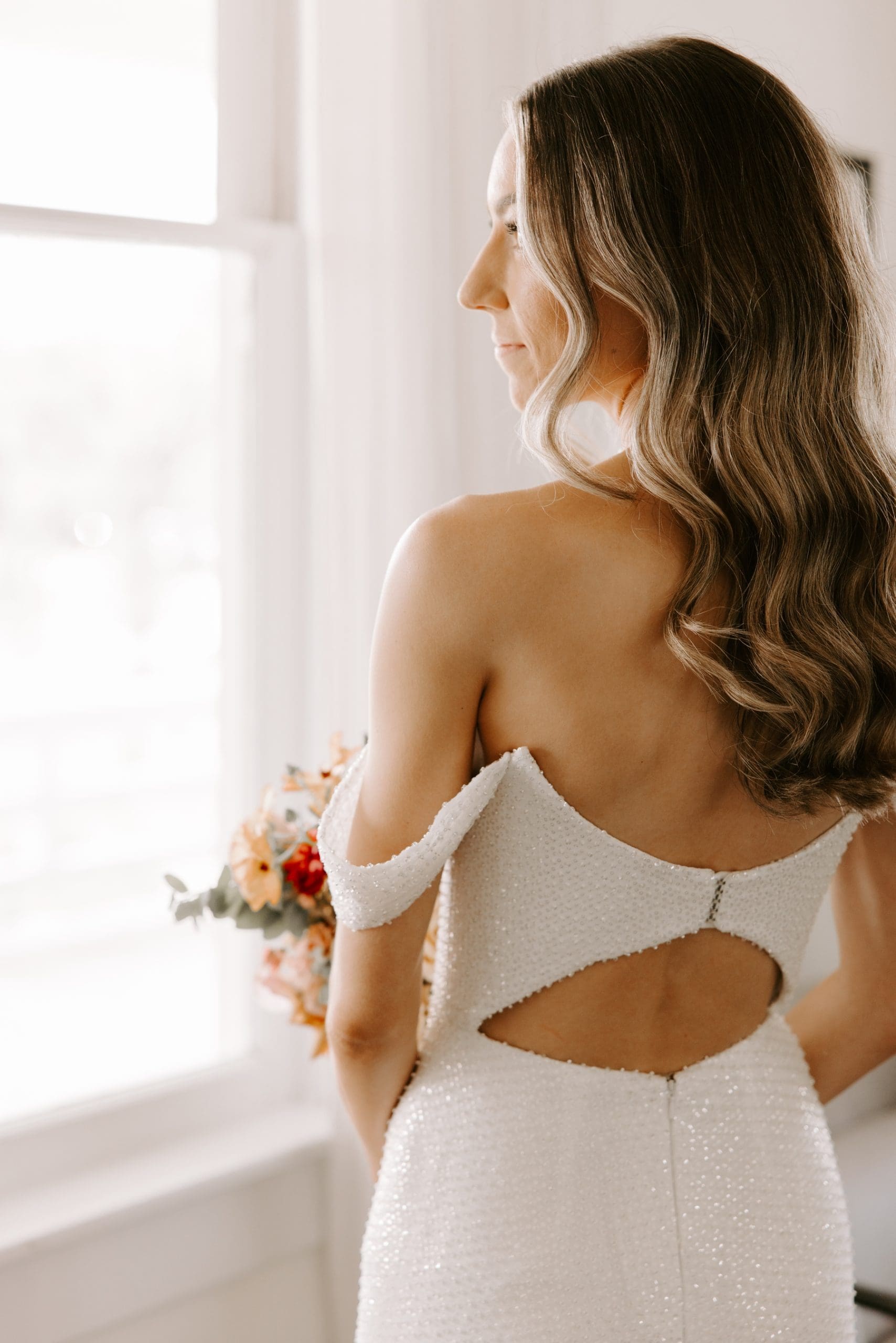 Bride facing away from camera wearing embellished dress with cutout in the back