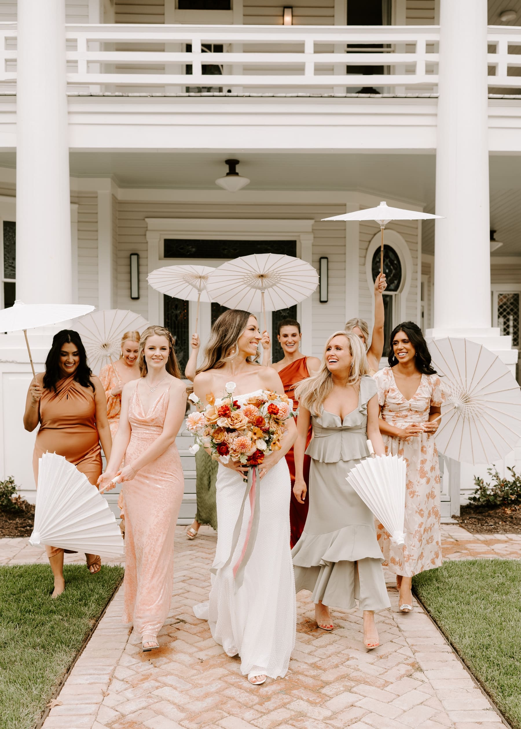 Bridesmaids holding parasols and walking with bride