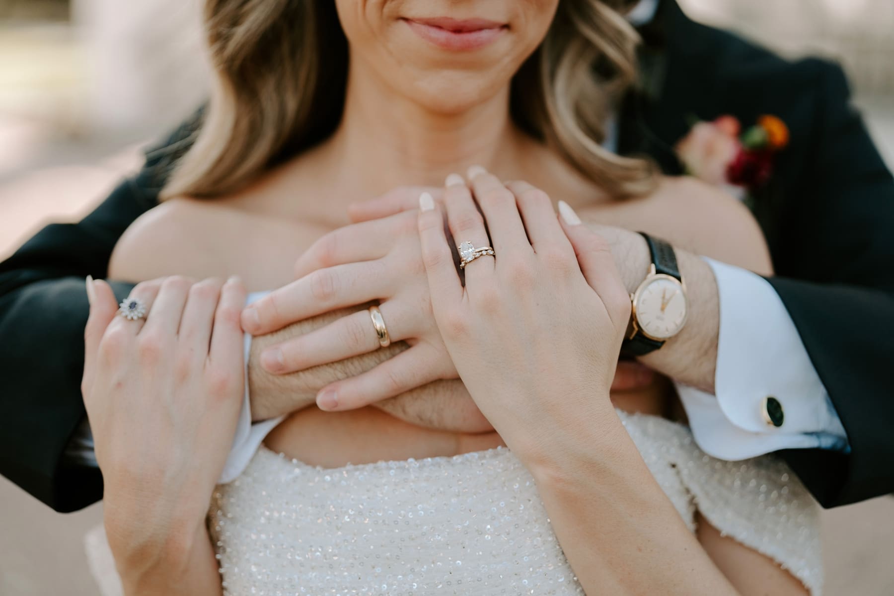 Groom hugging bride from behind with rings in clear view