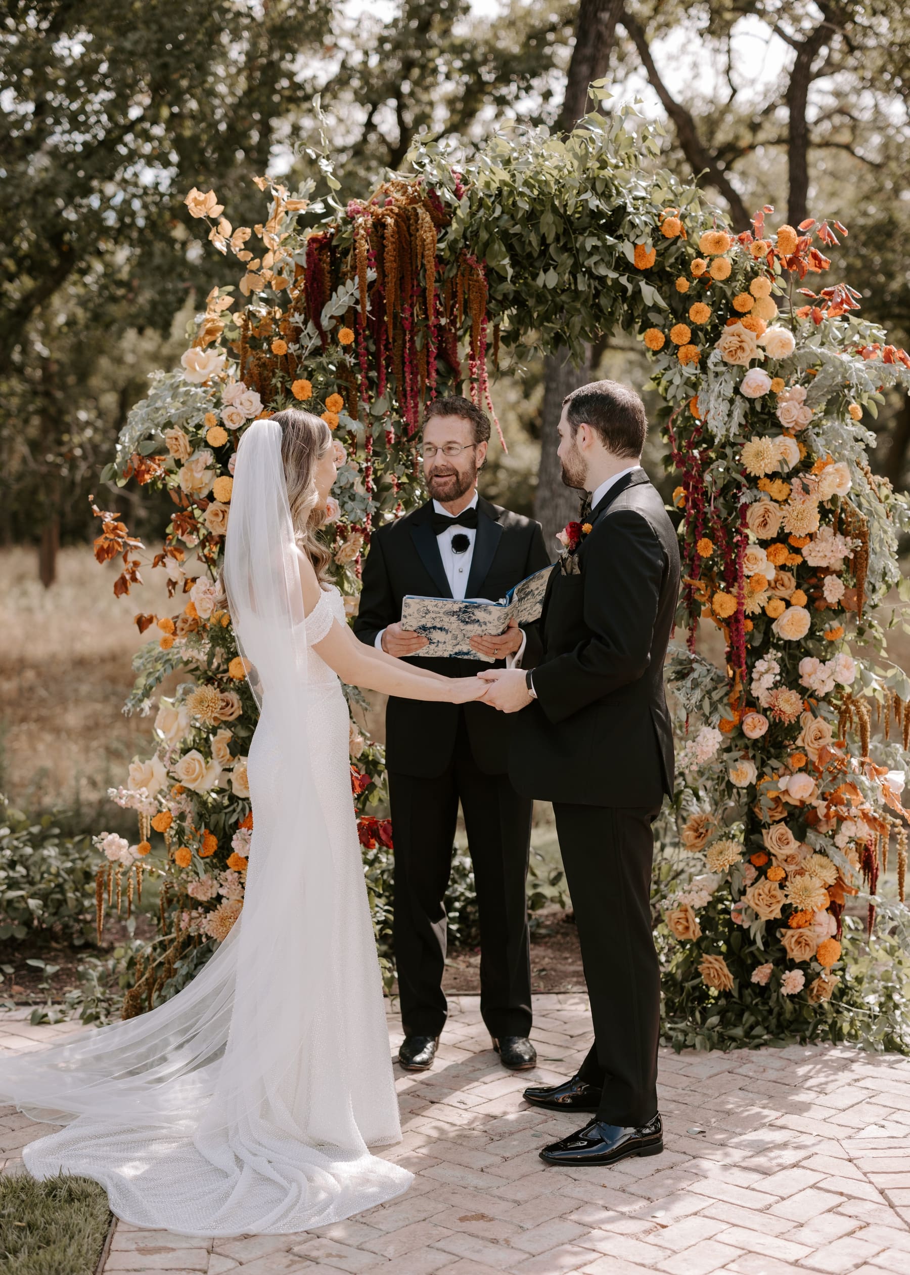 Bride and groom holding hands in front of boho arch at The Grand Lady Austin wedding ceremony