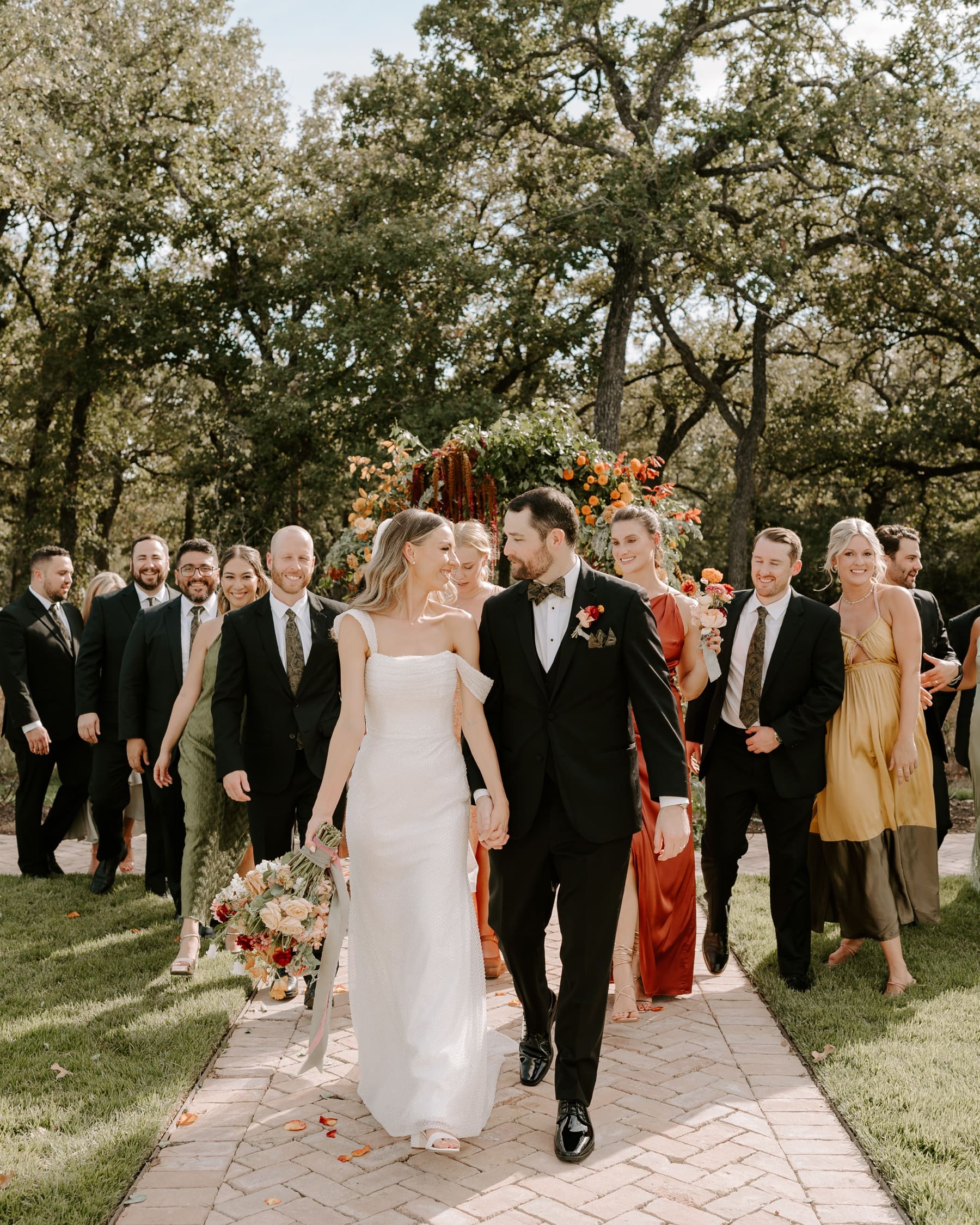 Bride and groom looking at each other with wedding party walking behind them