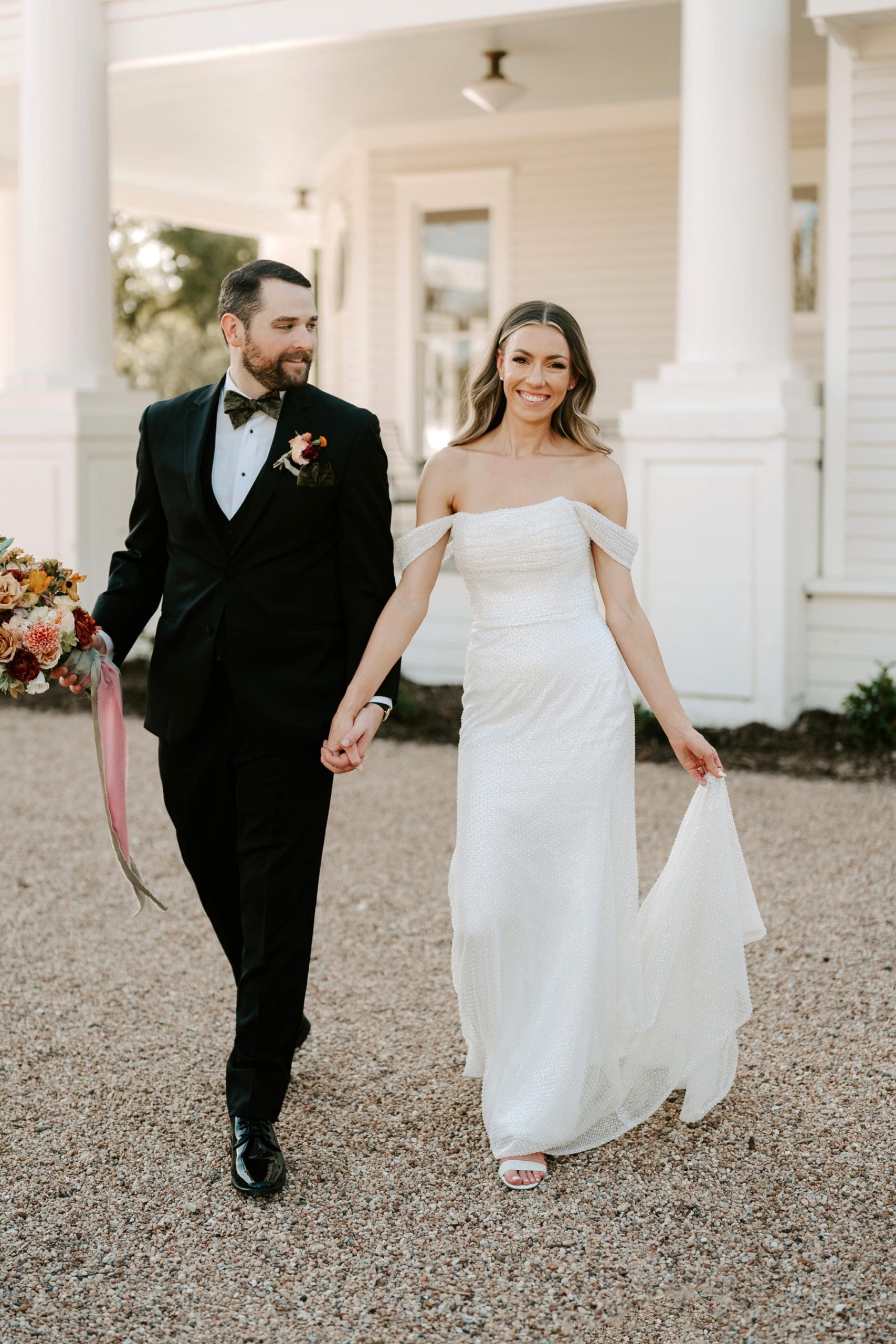 Bride and groom holding hands and walking with groom holding her bouquet 