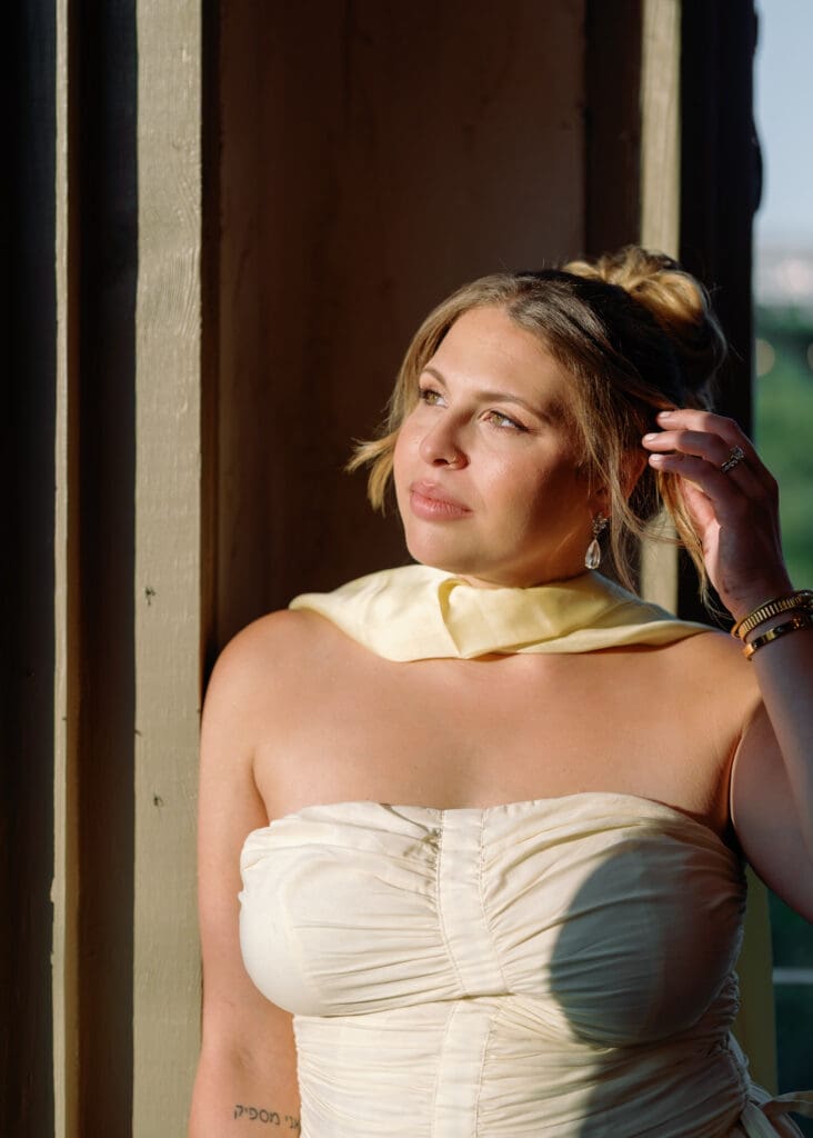 Close-up portrait of bride in soft golden light at Villa Antonia, wearing a ruched cream dress and yellow wrap during her Austin anniversary photoshoot.