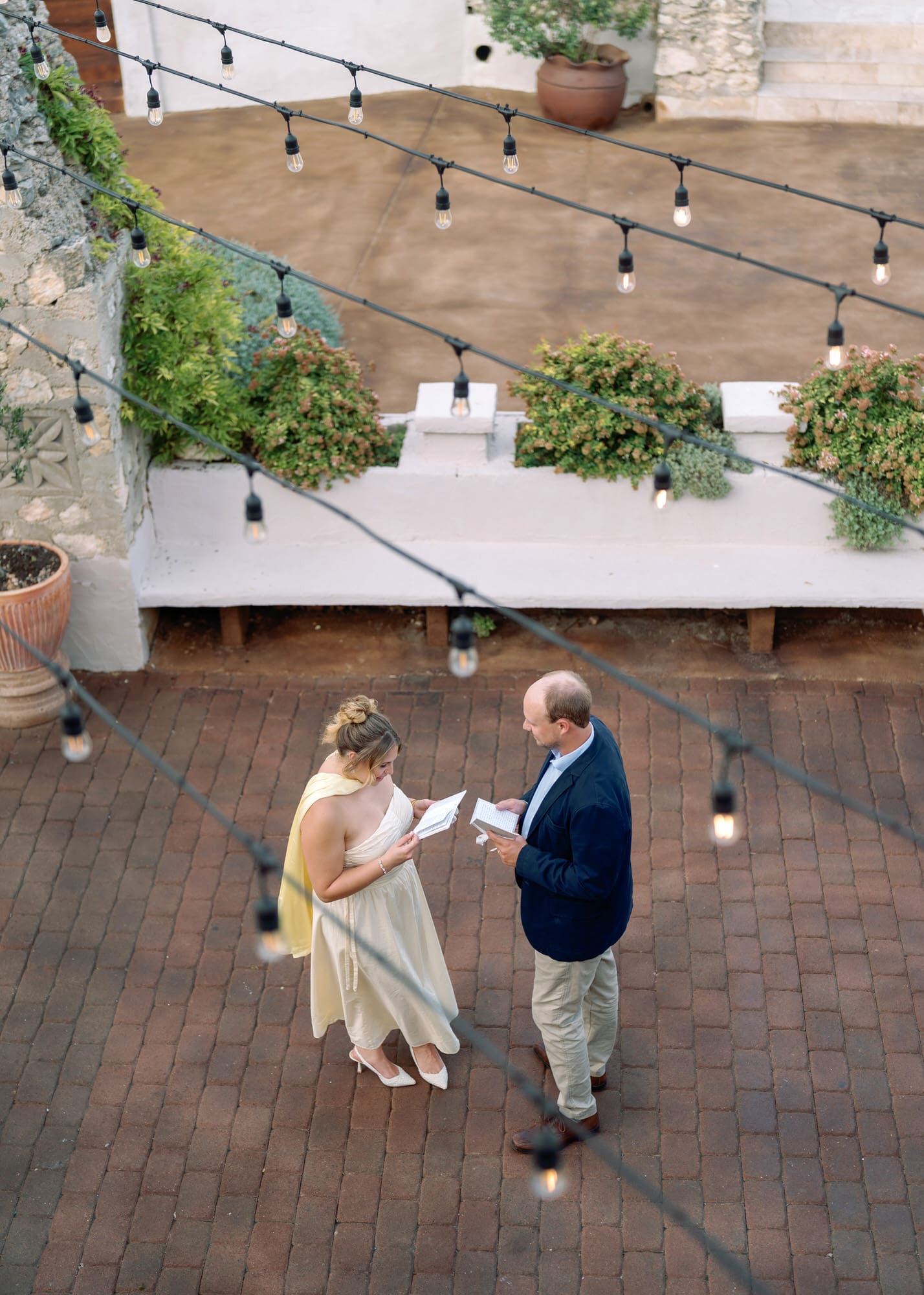Bride and groom reading their anniversary letters to each other under string lights at Villa Antonia courtyard.