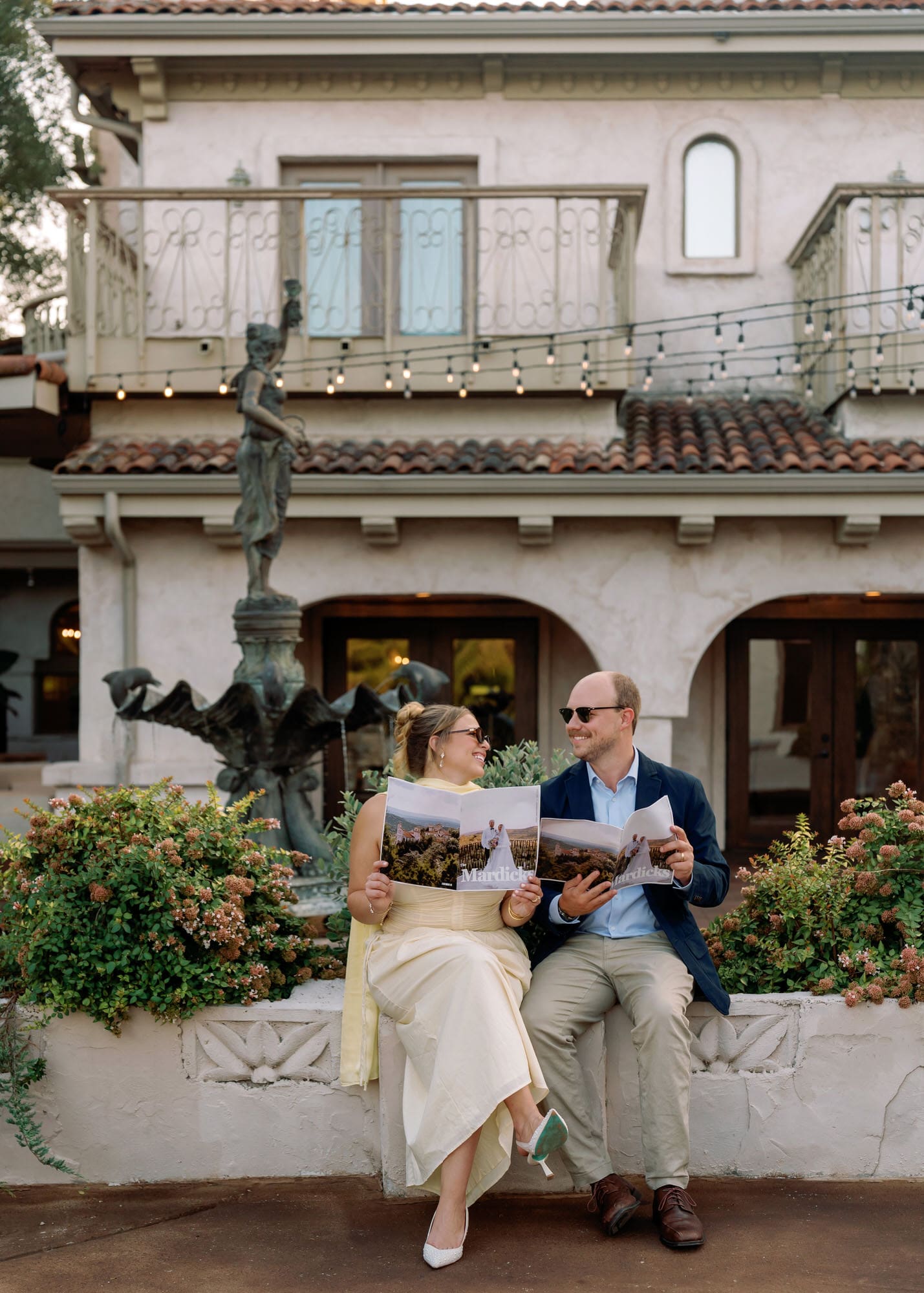 Couple sitting together, laughing and holding custom photo books recapping their first year of marriage
