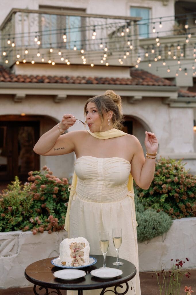 Bride enjoying a bite of their preserved wedding cake top with champagne on the table beside her during anniversary celebration at Villa Antonia.